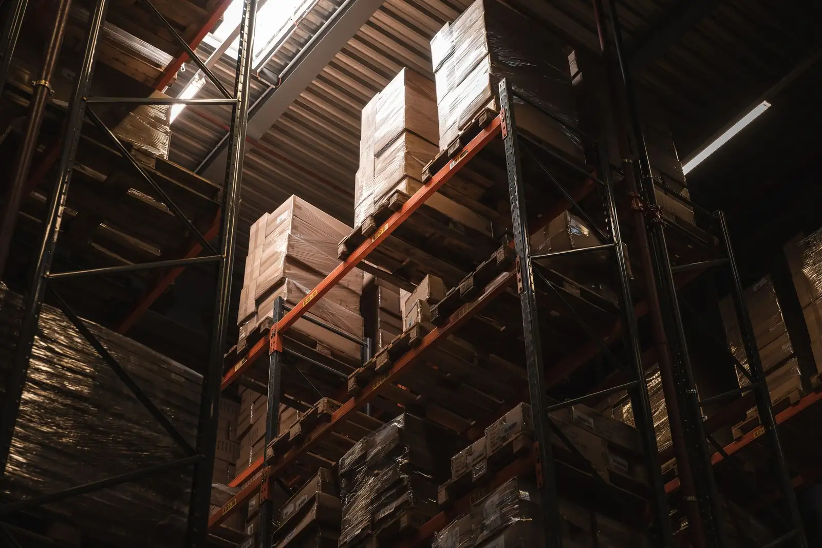 Warehouse racking stacked with cartons rising into shadow