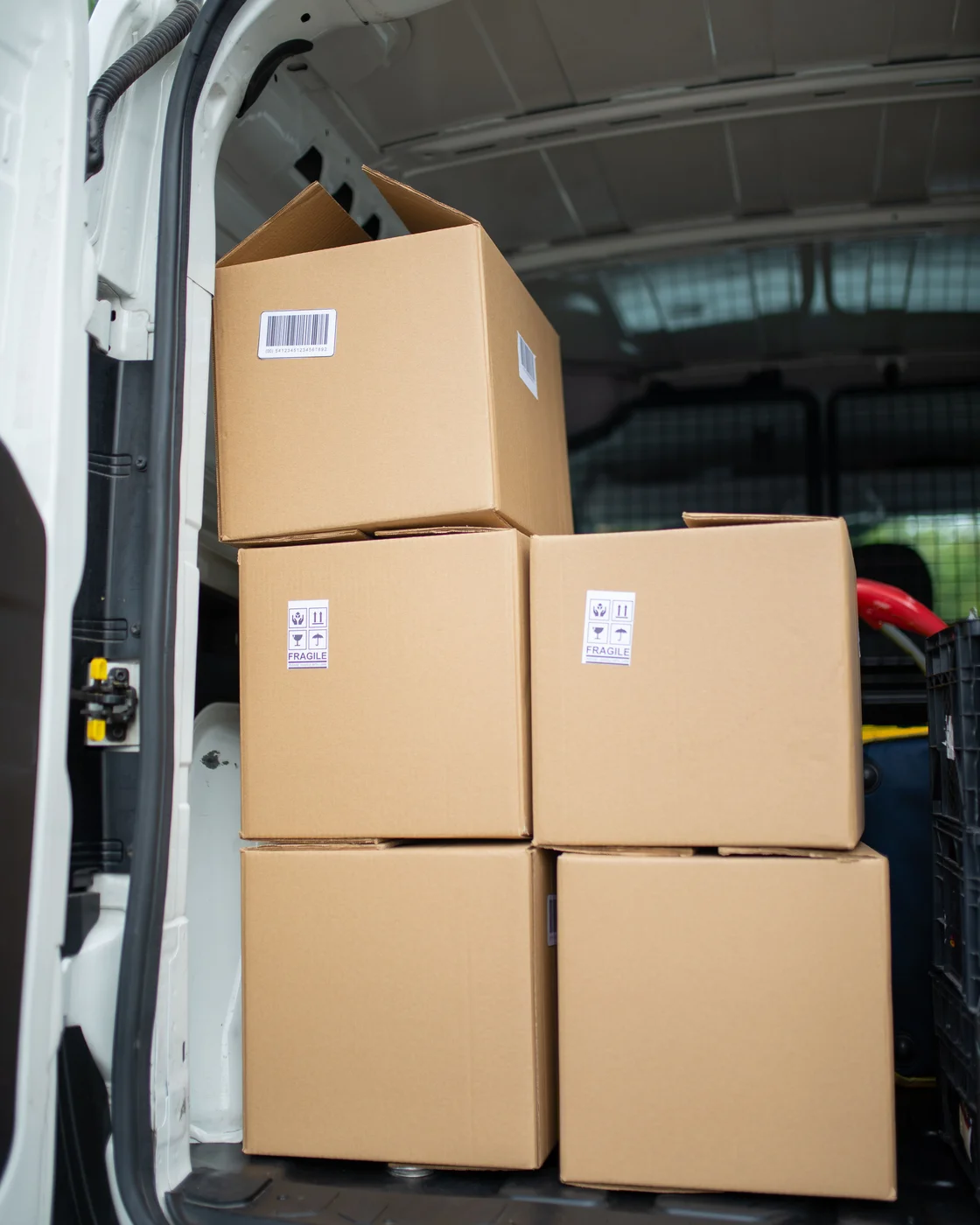 Cartons with handling labels stacked inside a delivery van ready for dispatch