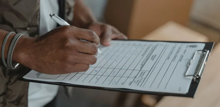 A hand writing on a paper docket beside a carton