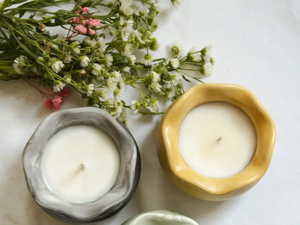 Three candles in stone vessels beside cut flowers