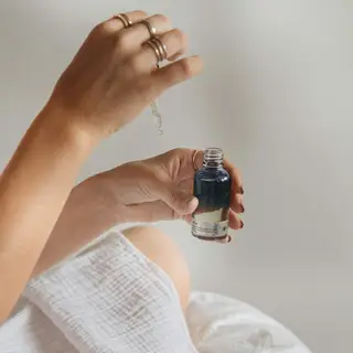 Hands holding a glass serum bottle and dropper